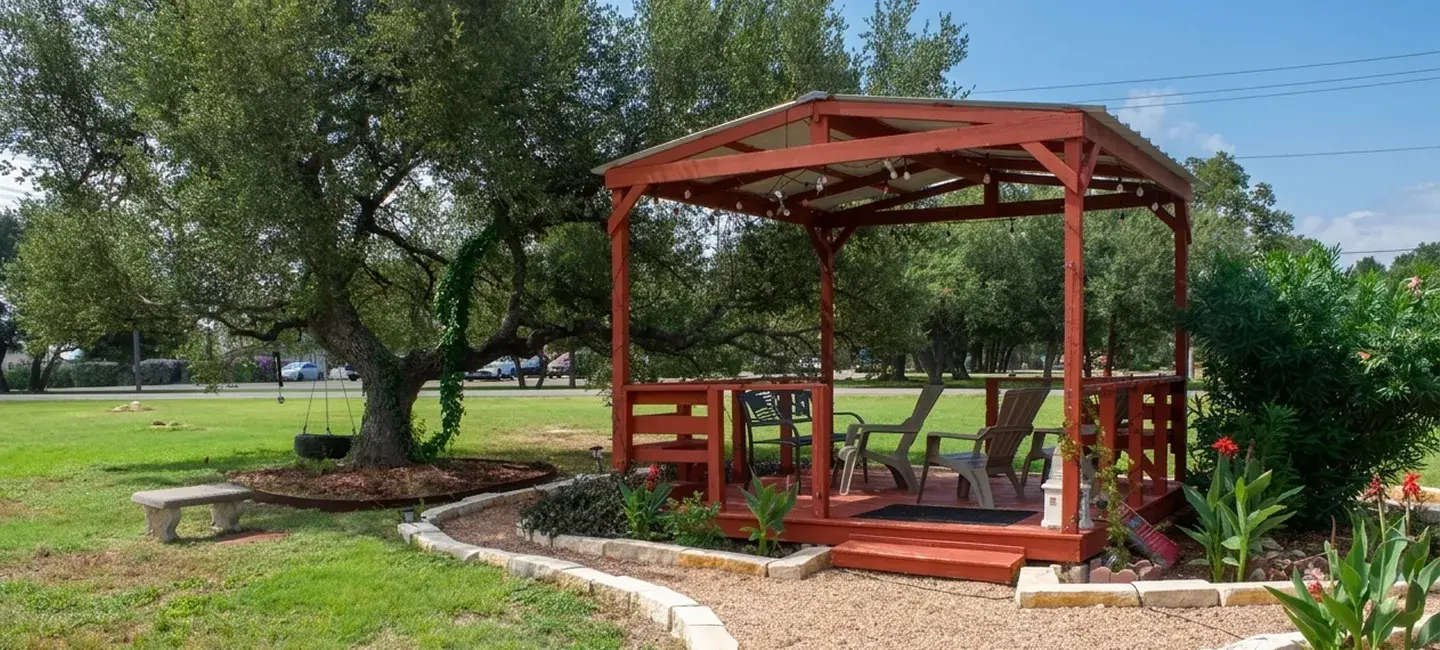Outpost Motel — red wooden patio gazebo under an oak tree in Dripping Springs, Texas